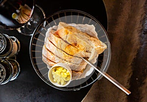 Sliced fresh baked artisan bread with butter in serving basket