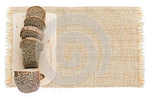 Sliced fresh bread on wooden cutting board and on sackcloth isolated on white background