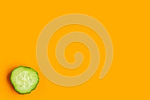 Sliced fresh cucumber isolated on orange background, top view, minimal concept, copy space