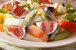 Sliced fresh fruit: figs, peaches, melons, kiwi and orange close