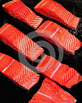 Sliced fresh salmon fillets on black background