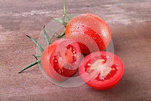 Sliced fresh tomatoes with green leaves on wooden background
