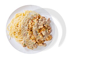 Sliced fried chicken meat in a creamy sauce with spaghetti pasta in a plate. top view