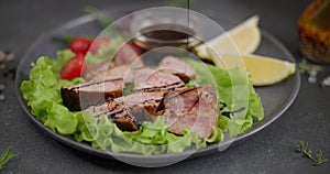 Sliced Fried grilled piece of Organic Tuna Steak on a black ceramic plate with salad