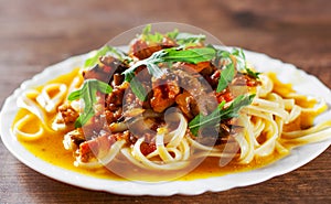 Sliced fried meat with vegetables and mushrooms in a sauce with bavette pasta in a plate photo