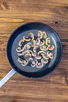Sliced fried mushrooms champignons spread out in a pan on a wooden table