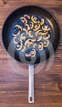 Sliced fried mushrooms champignons spread out in a pan on a wooden table