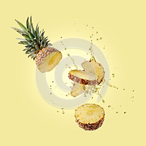 Sliced fruit ananas pineapple with splashing drink juice flying isolated on yellow color background