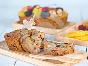 Sliced Fruit cake in wooden plate with wooden spoon and fork