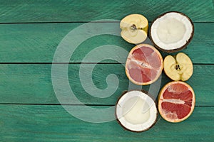 Sliced fruit - grapefruit, coconut, apple, on a wooden background.
