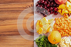 Sliced fruits and vegetables for smoothies. Orange, cherry and others. Top view, on a wooden table