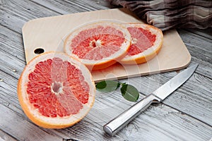 Sliced grapefruit on a cutting board on a light wooden background