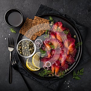 Sliced Gravlax,  scandinavian beet cured salmon  served with red onion, capers,  lemon and crisp bread photo