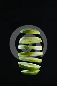 Sliced green apple levitates on black background