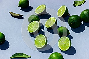Sliced green and juicy limes and lemons on a blue background with hard shadows