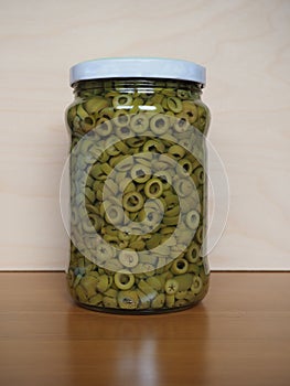 Sliced green olives in brine in glass jar