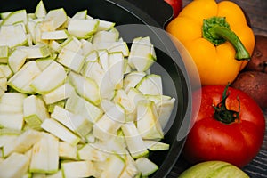 Sliced green zucchini. Red tomatoes and colored bell peppers on a dark wooden background. Raw vegetables. Young potatoes and