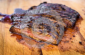 Sliced grilled juicy marinated angus beef flank steak on wooden board