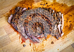 Sliced grilled juicy marinated beef flank steak on wooden board