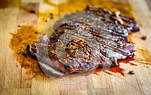 Sliced grilled juicy marinated beef flank steak on wooden board