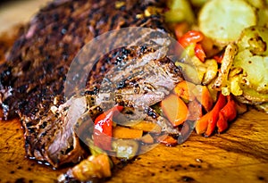 Sliced grilled juicy marinated beef flank steak on wooden board