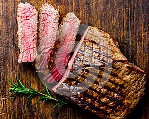 Sliced grilled medium rare beef steak served on wooden board Barbecue, bbq meat beef tenderloin. Top view, slate