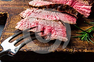 Sliced grilled medium rare beef steak served on wooden board Barbecue, bbq meat beef tenderloin. Top view, slate