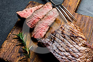 Sliced grilled medium rare beef steak served on wooden board Barbecue, bbq meat beef tenderloin. Top view, slate background