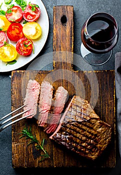 Sliced grilled medium rare beef steak served on wooden board Barbecue, bbq meat beef tenderloin. Top view, slate background