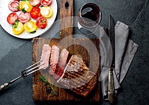 Sliced grilled medium rare beef steak served on wooden board Barbecue, bbq meat beef tenderloin. Top view, slate background