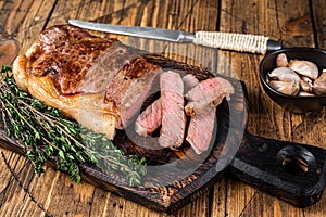 Sliced Grilled new york strip beef meat steak or striploin on a wooden board. wooden background. Top view