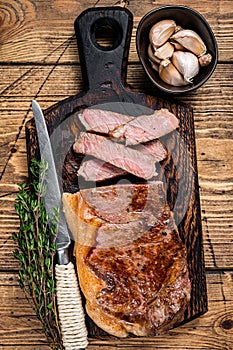 Sliced Grilled new york strip beef meat steak or striploin on a wooden board. wooden background. Top view