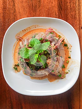 Sliced grilled pork salad Thai food on wood background