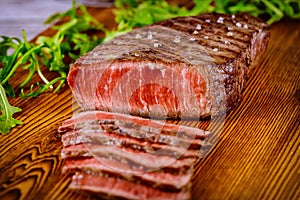 Sliced grilled rare beef steak served on wooden board