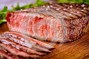 Sliced grilled rare beef steak served on wooden board