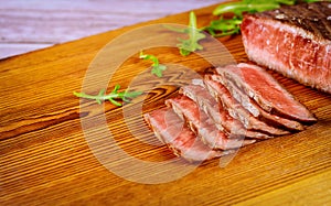 Sliced grilled rare beef steak served on wooden board
