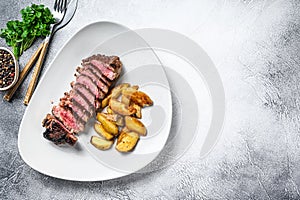 Sliced Grilled rump Beef steak with potato. White background. Top view. Copy space