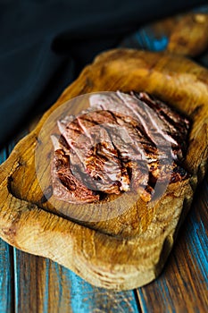 Sliced grilled steak medium rare served on wooden cutting board with vegetables