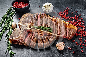 Sliced Grilled T-bone steak. Cooked tbone beef meat. Black background. Top view photo