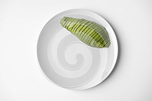Sliced half avocado on a plate on white background with copy space. Close-up, top view