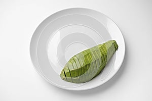 Sliced half avocado on a plate on white background with copy space. Close-up, top view