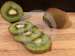 Sliced, half and full kiwi on cutting board