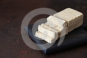 Sliced halva on a wooden tray on a brown background. Oriental sweets photo