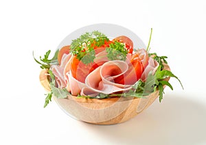 Sliced ham with arugula and tomatoes