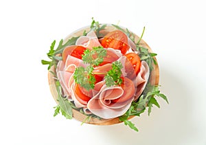 Sliced ham with arugula and tomatoes