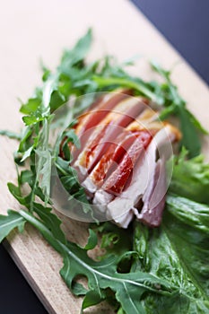 Sliced ham with fresh green lettuce leaves on a cutting board.