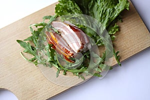Sliced ham with fresh green lettuce leaves on a cutting board.