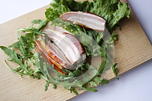 Sliced ham with fresh green lettuce leaves on a cutting board.