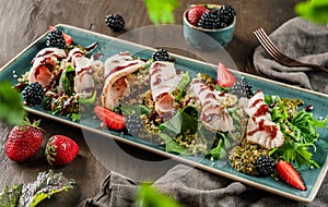Sliced ham meat with quinoa porridge, salad and blackberry sauce in plate on wooden background. Healthy food, clean eating,