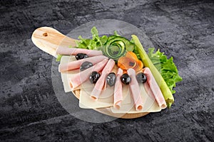 Sliced ham salami decorated on wooden board with olives, tomato and lettuce and clipping path